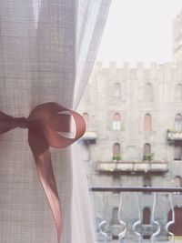 Close-up of window curtain tied with ribbon at home