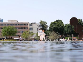 People by swimming pool in city against clear sky