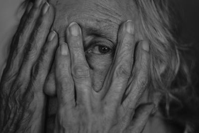 Close-up portrait of senior woman covering face with hands