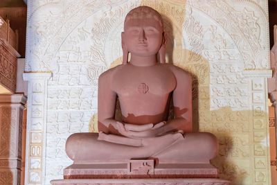 Isolated red stone jain god holy statue in meditation from different angle