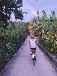 Rear view of people riding bicycle on road