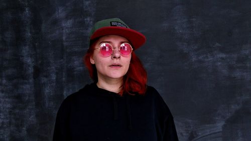 Portrait of young woman standing against wall