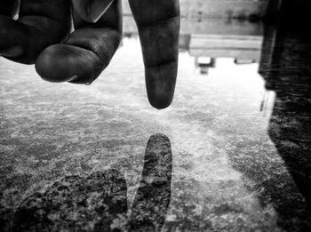 Human index finger almost  touching a pool of water