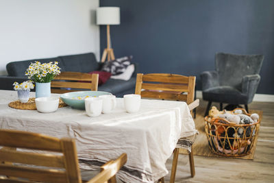 Table with flowers chamomile on linen tablecloth in living room, bright interior, cottagecore