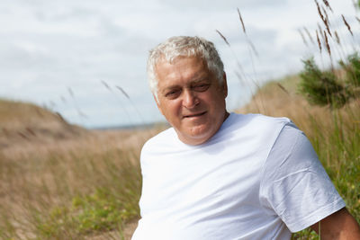 Mature man looking away while sitting on field