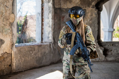 Caucasian woman in army uniform holding a machine gun.