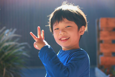 Portrait of smiling boy gesturing in sunny day