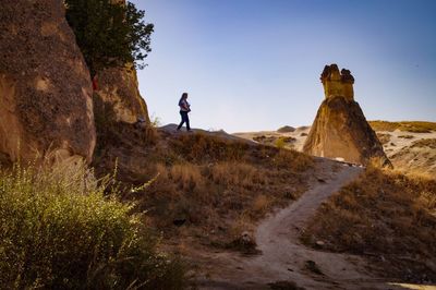 Man standing on rock by land against sky