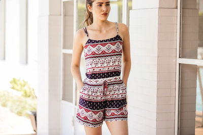 Beautiful young woman standing against wall