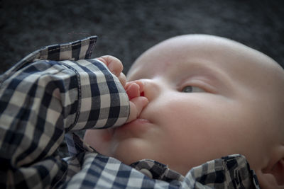 High angle close-up of cute baby boy looking away while lying on bed at home