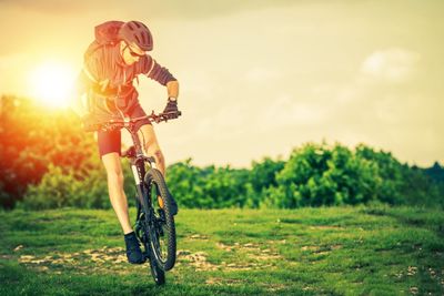 Full length of man cycling on grassy field