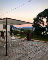 Empty chairs and tables against sky during sunset