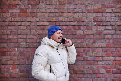 Full length of young man standing against brick wall