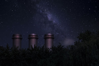 Low angle view of smoke stacks against sky at night