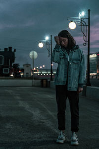 Portrait of young woman standing on street at night