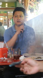 Portrait of young man sitting at restaurant table