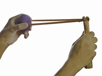 Close-up of hand holding cross against white background