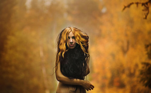 Portrait of woman standing in forest during autumn