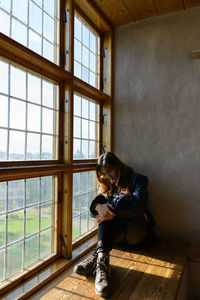 Woman sitting by window at home
