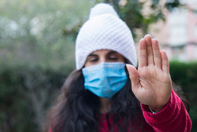 Young latin woman with medical mask making stop or denial sign