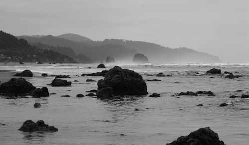 Idyllic view of beach against mountains and sky at ecola state park