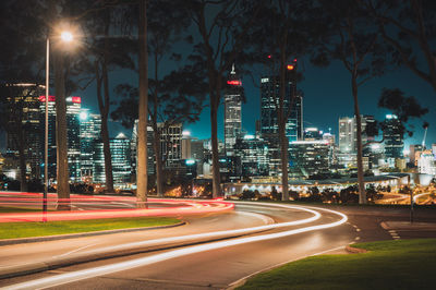 Light trails on city street by buildings at night