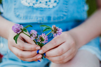 Midsection of girl hand holding purple flowers