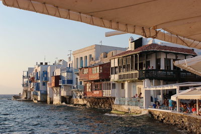 Buildings by sea against clear sky