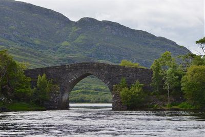 Arch bridge over river against sky