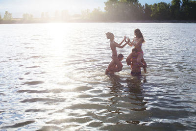 Male friends carrying women on shoulders while enjoying in river