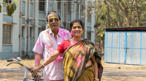 An indian senior couple with colorful faces playing holi - the festival of colors