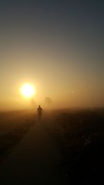 Silhouette man on landscape against sky during sunset
