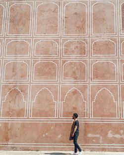 Side view of woman standing against wall