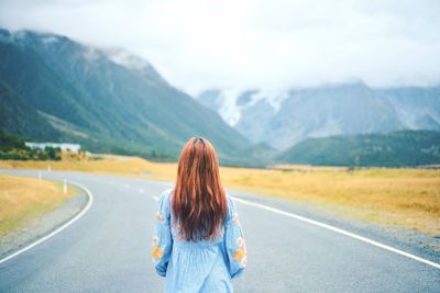 Rear view of woman on road against mountain range