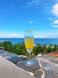 Wineglass on beach against blue sky
