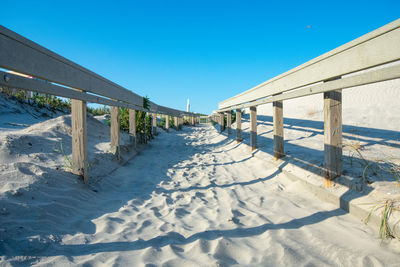A sandy beach path with a wooden fence on each side casting shadows in wildwood new jersey