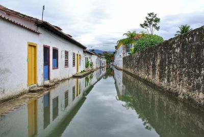 Canal amidst houses against sky