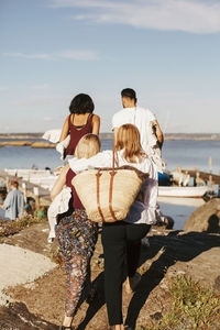 Rear view of friends walking towards harbor for party against sky