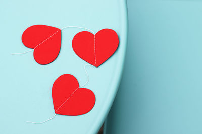 Paper red hearts garland in woman girl hands on wooden board table,light blue metal or in glass