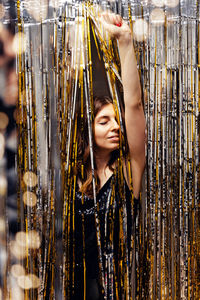 Woman dancing on new year party, festive curtain decor and blurred lights