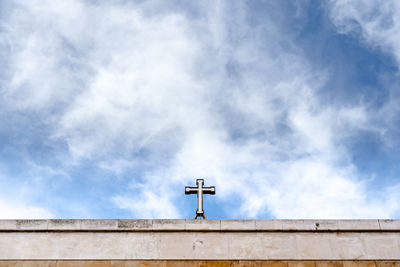 Low angle view of cross on building against sky