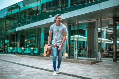 Full length portrait of smiling young man standing in city