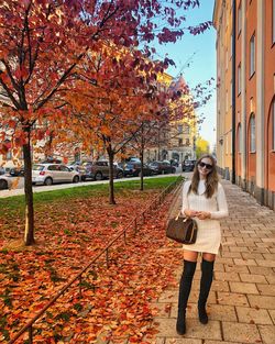 Full length portrait of woman standing in city during autumn