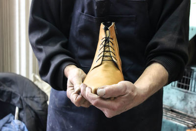 Midsection of man holding shoe