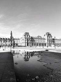 The louvre reflecting in puddle on street