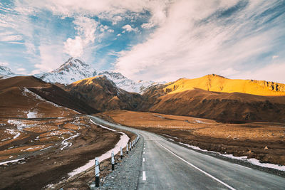 Road amidst mountains against sky during sunset