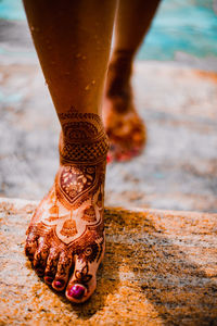 Low section of woman wearing shoes on beach