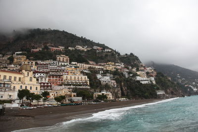 Scenic view of beach by buildings against sky