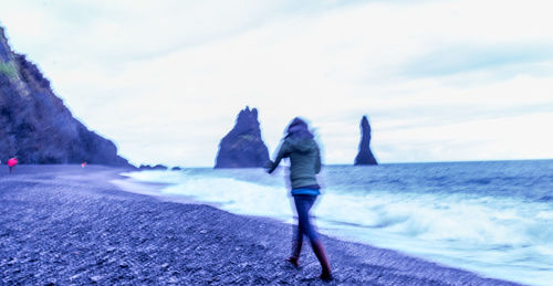 Man standing on sea shore against sky