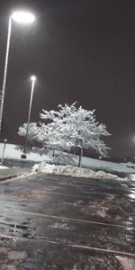 Snow covered street lights against sky at night